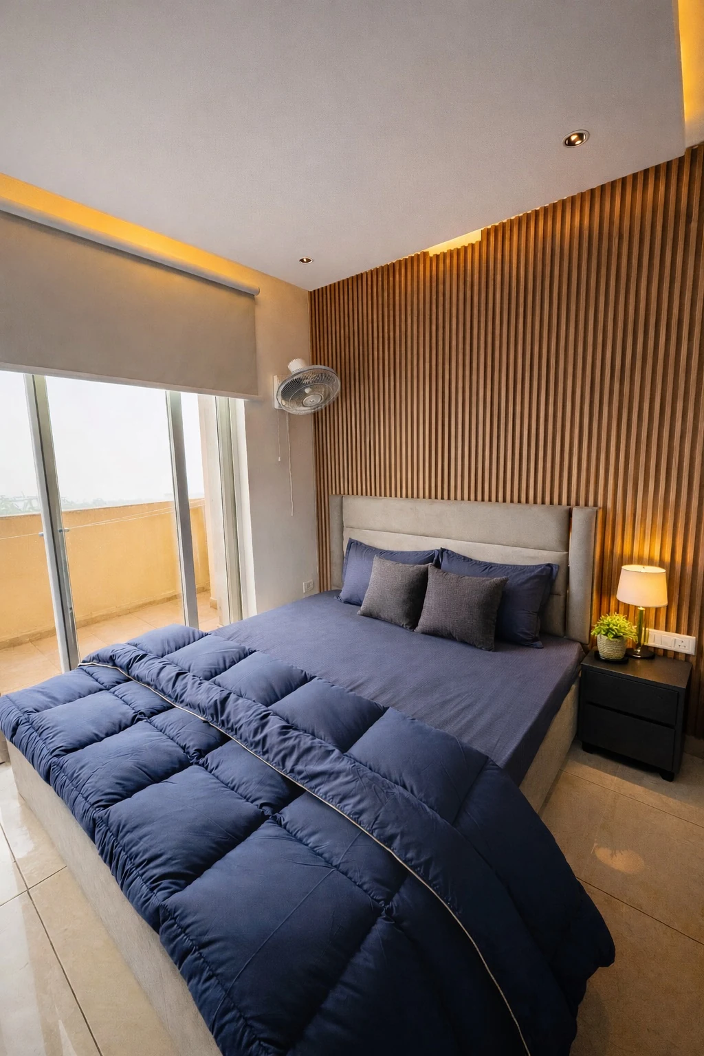 King bedroom with fluted wood wall and balcony access at Sukoon 1BHK